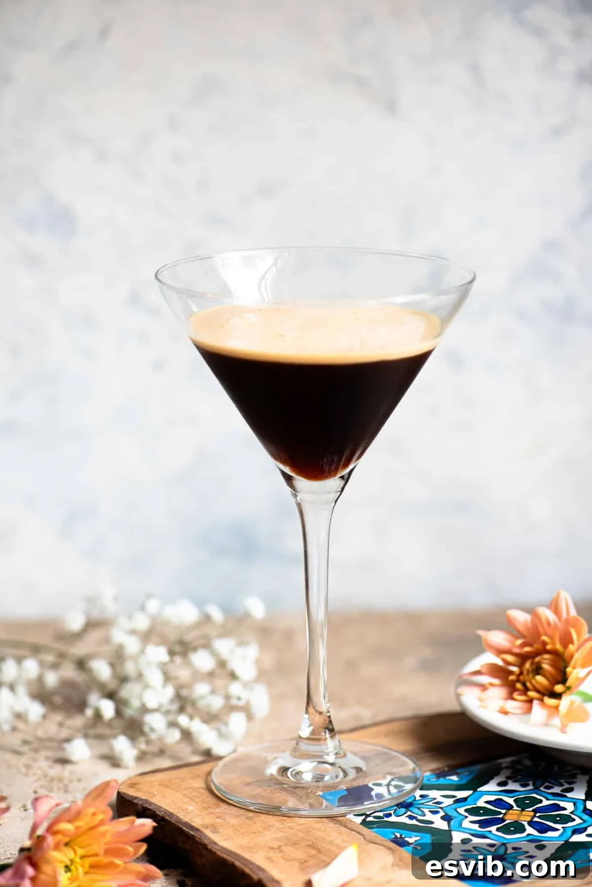 Caffe Shakerato: Classic Italian Iced Coffee Recipe 11 A martini glass filled with an Italian iced coffee sitting on a wooden table with flowers around.