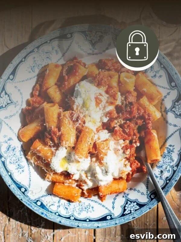 Spicy Calabrian sausage ragu in a blue and white bowl with stracciatella on top.