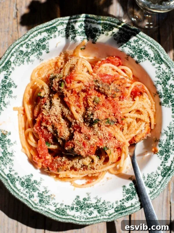 An overhead shot of spaghetti in a tomato sauce with sardines and breadcrumbs on top.