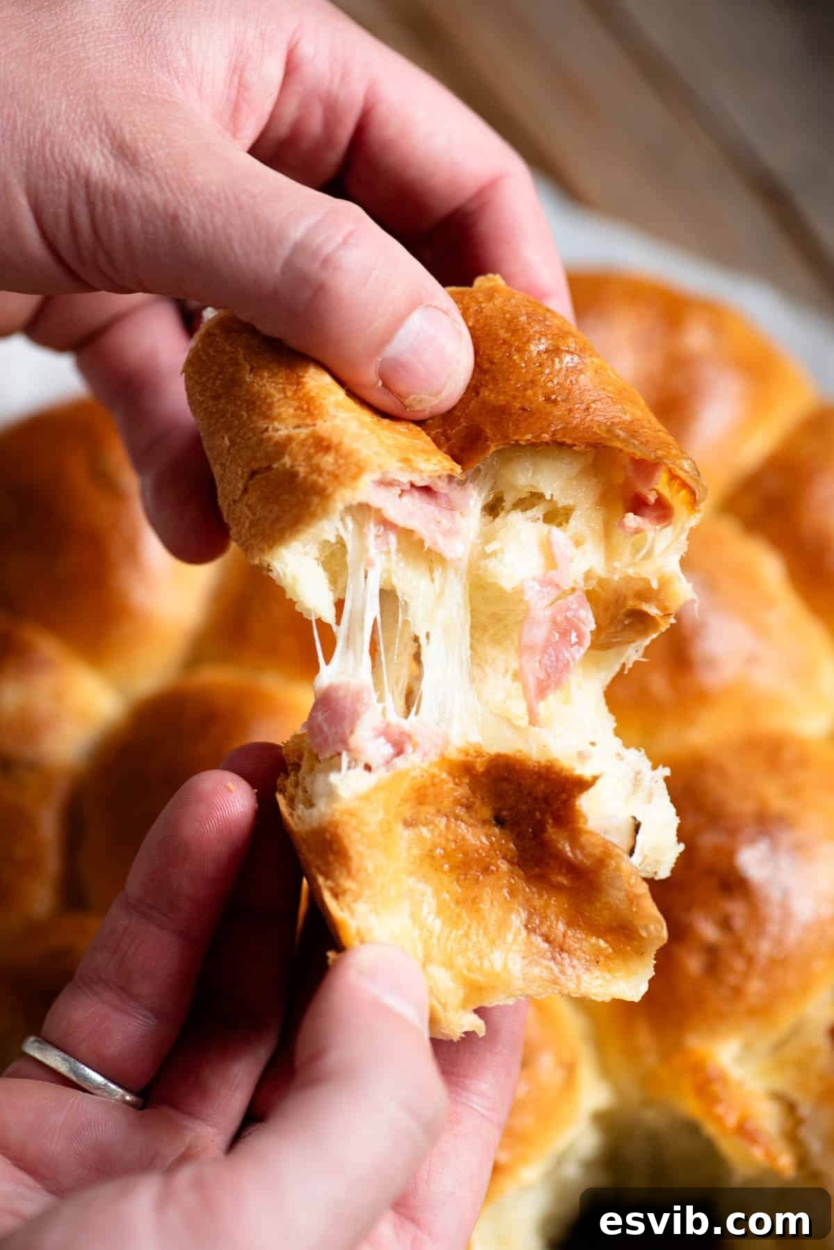 Neapolitan Danubio: Savory Stuffed Brioche Buns 4 A hand tearing open a piece of danubio salato to show the cheese pull and ham inside.