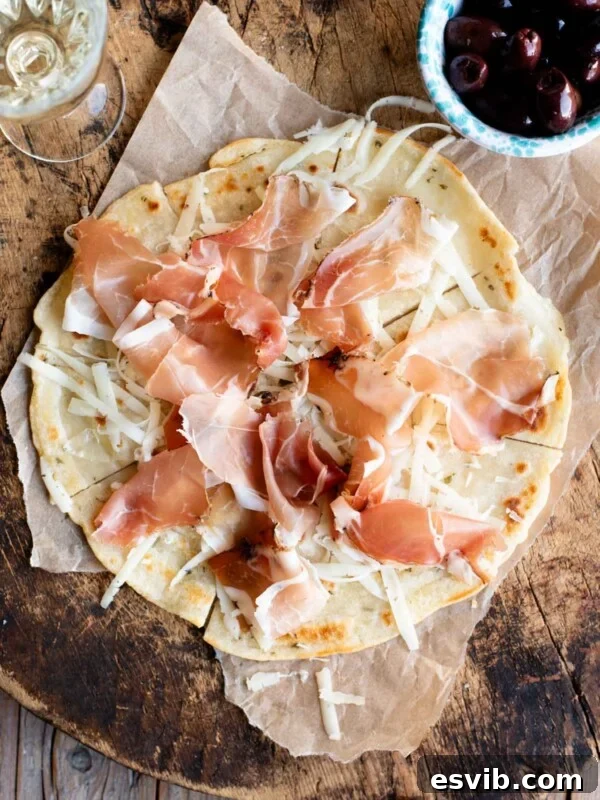Neapolitan Danubio: Savory Stuffed Brioche Buns 7 An overhead shot of Brustengo, an Italian flatbread topped with cured meat and cheese on a wooden board.